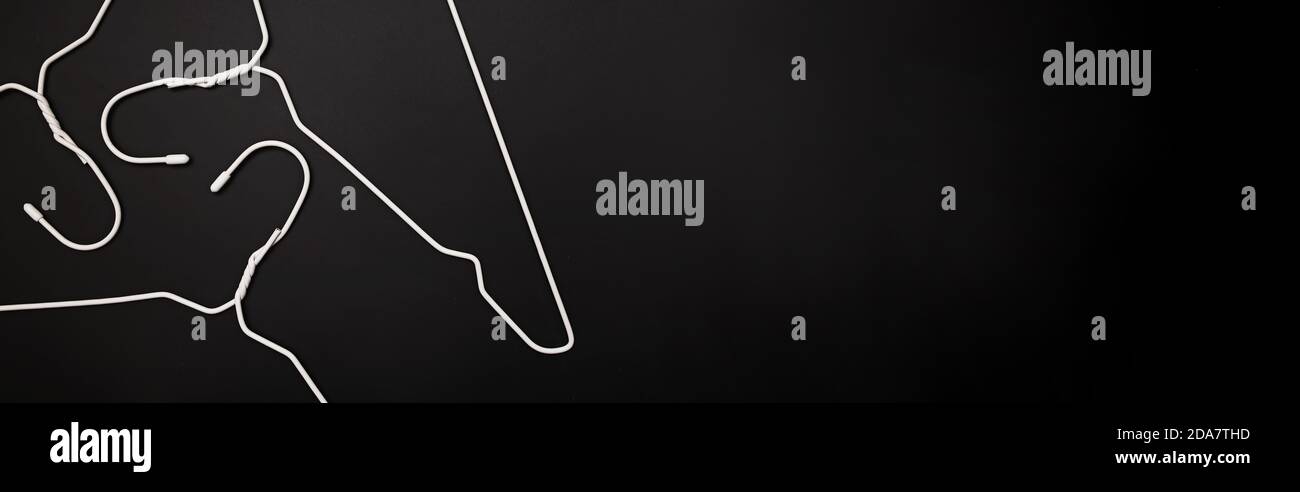 Empty white hangers lying on black background Stock Photo