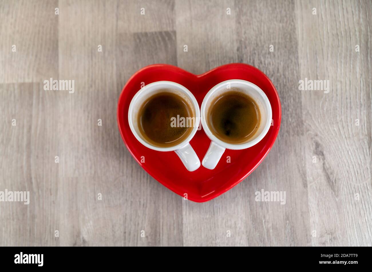 two cups of coffee with a red ceramic heart saucer Stock Photo