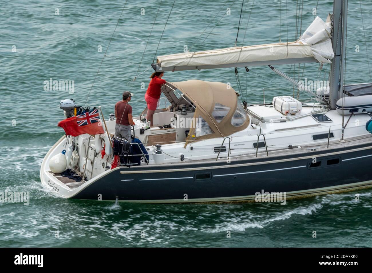 a man or skipper steering at the helm of a large fast cruising yacht on the solent near lymington, hampshire. Stock Photo