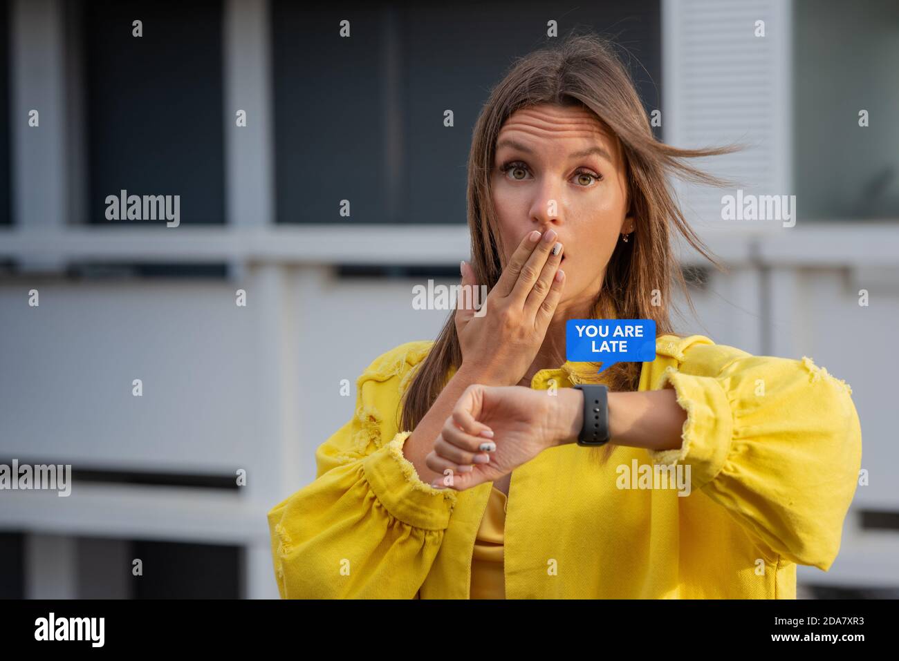Young woman reading message on a smartwatch and feels shocked because she is late. Forgot about a meeting or workday. Stock Photo