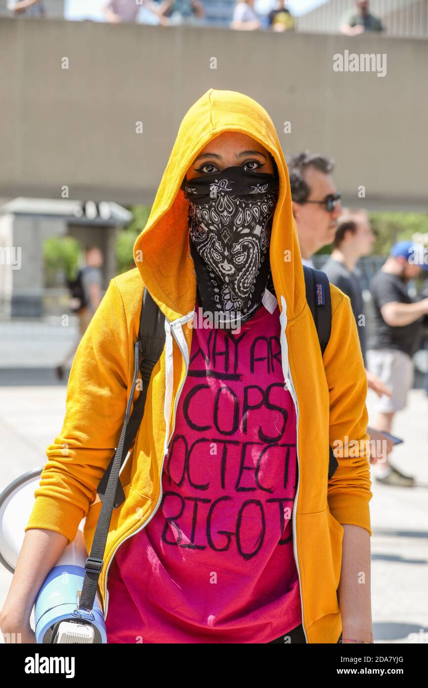 A masked protester wearing a shirt that reads 'Why do cops protect bigots' during the demonstration.A 'Stop the Hate' rally was held by ANTIFA (Anti-Fascist) protesters at Nathan Phillip Square in opposition to WCAI (Worldwide Coalition Against Islam) Canada, a group that planed a protest on the same day. Stock Photo