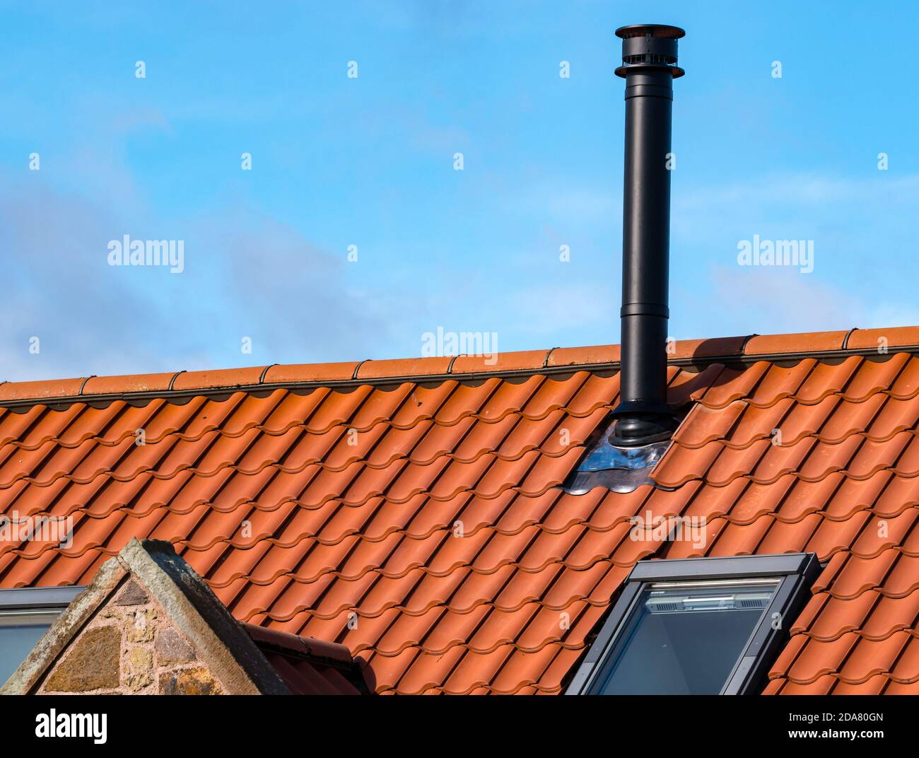 Flue for wood burning stove on house pantile roof in converted old farm building, East Lothian, Scotland, UK Stock Photo