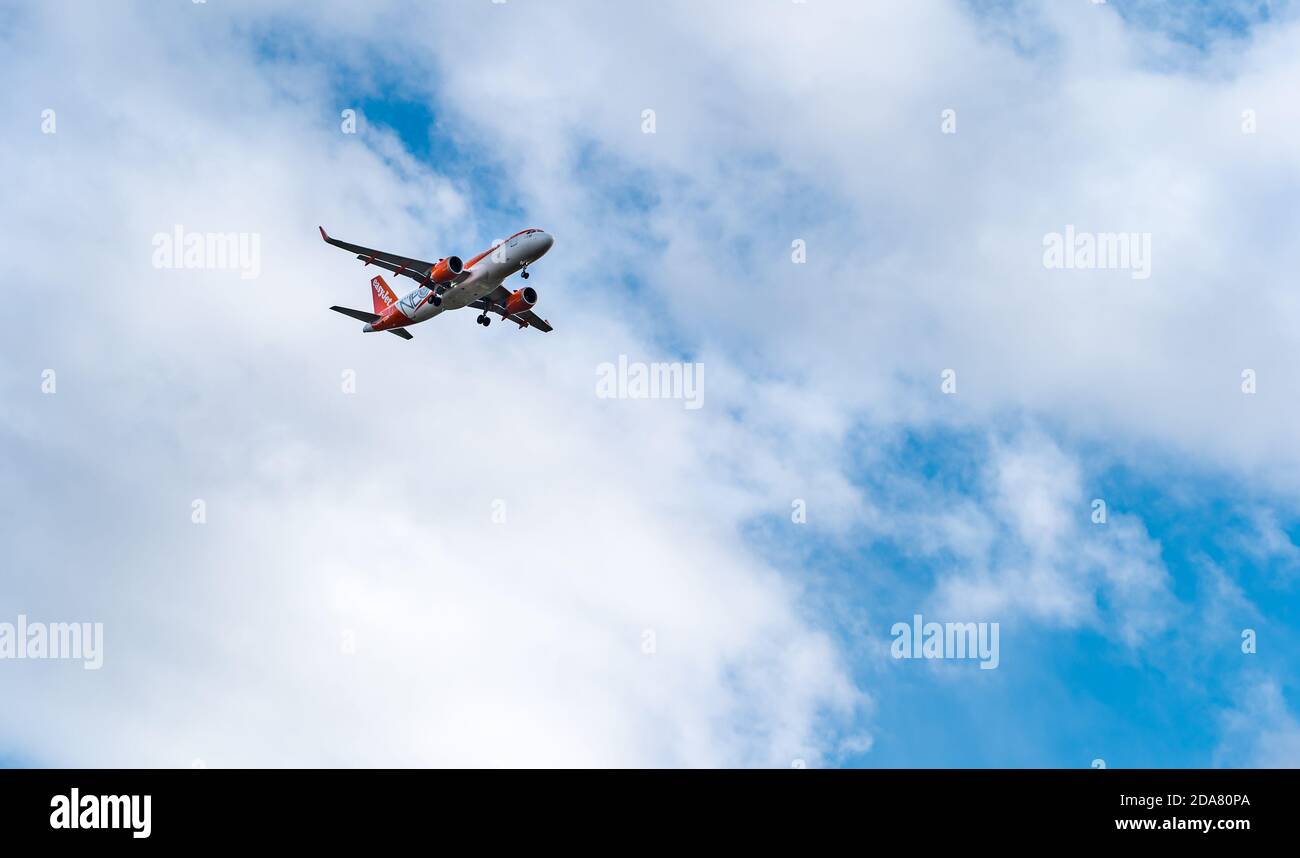 Easyjet aeroplane flying above in clouds and blue sky, Scotland, UK Stock Photo
