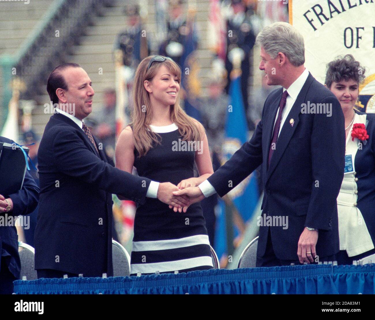 United States President Bill Clinton, right, shakes the hand of music producer and CEO of Sony Music Tommy Mottola, as singer Mariah Carey, center, looks on at the United States Capitol during the 15th Annual National Peace Officers Memorial Day Service in Washington, DC on May 15, 1996. Photo by Francis Specker Stock Photo