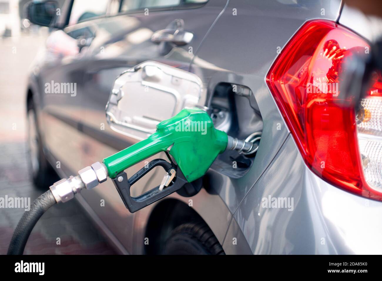 Man at a petrol pump fuel station inserting nozzle into fuel tank of a