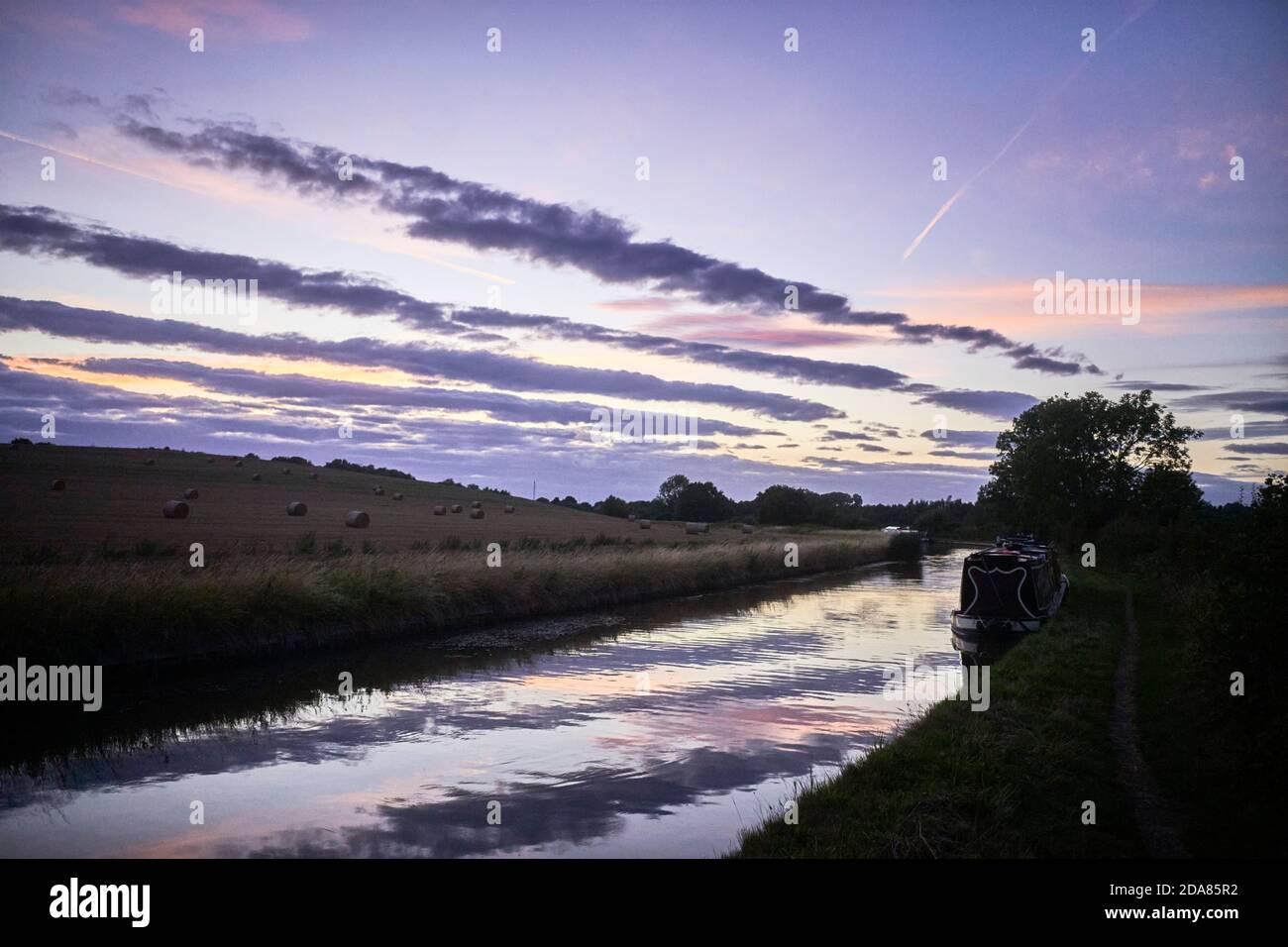 Sunset over the Coventry Canal near Atherstone with narrowboats moored up for the night Stock Photo