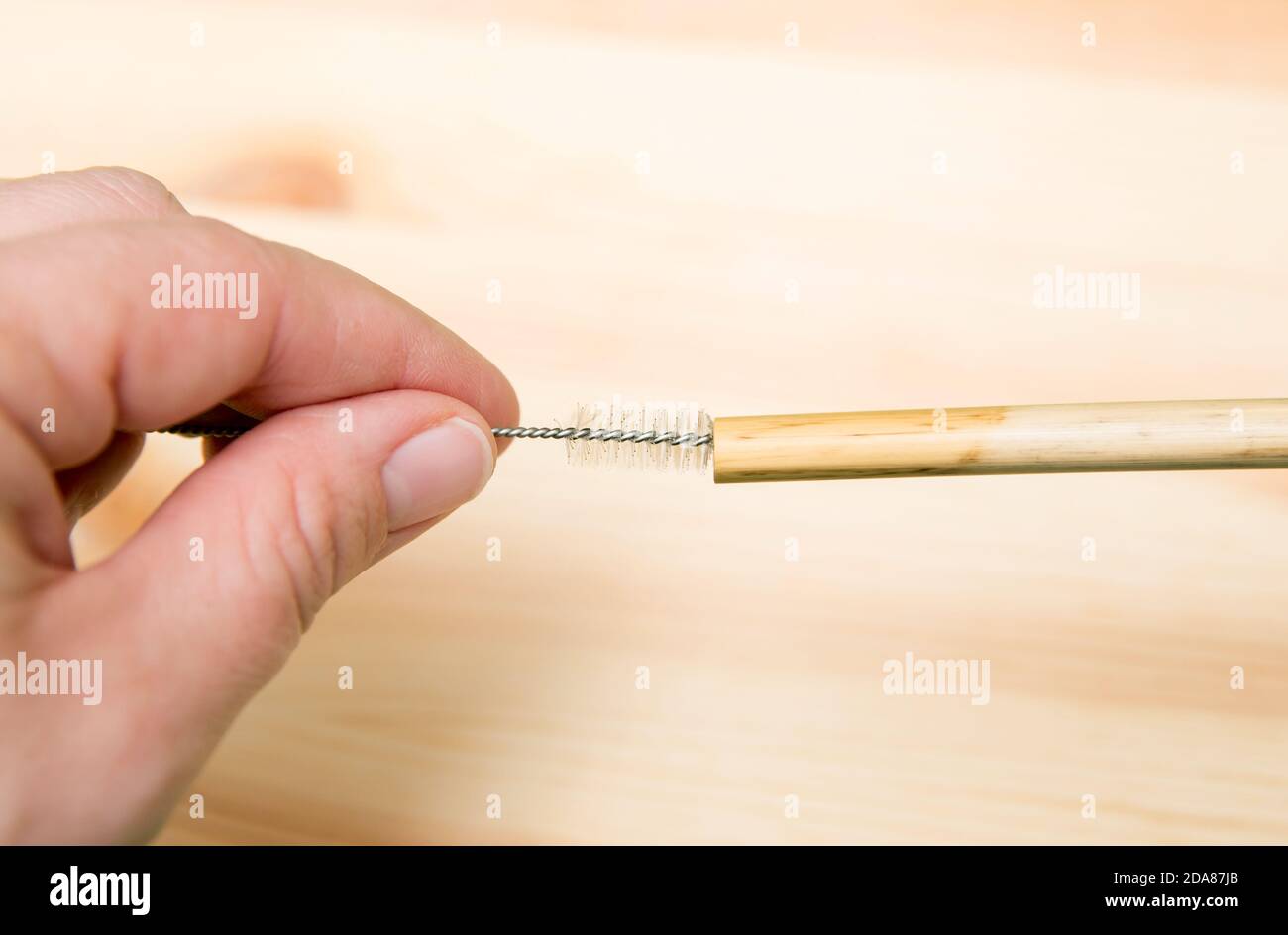 Close up view of person using drinking straw cleaner brush to clean reusable bamboo drinking