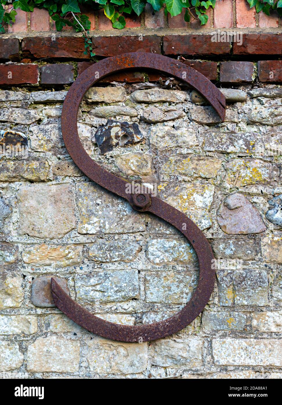 Anchor plate or wall support on old external flint and brick wall in the village of Itchenor, West Sussex, England, UK Stock Photo