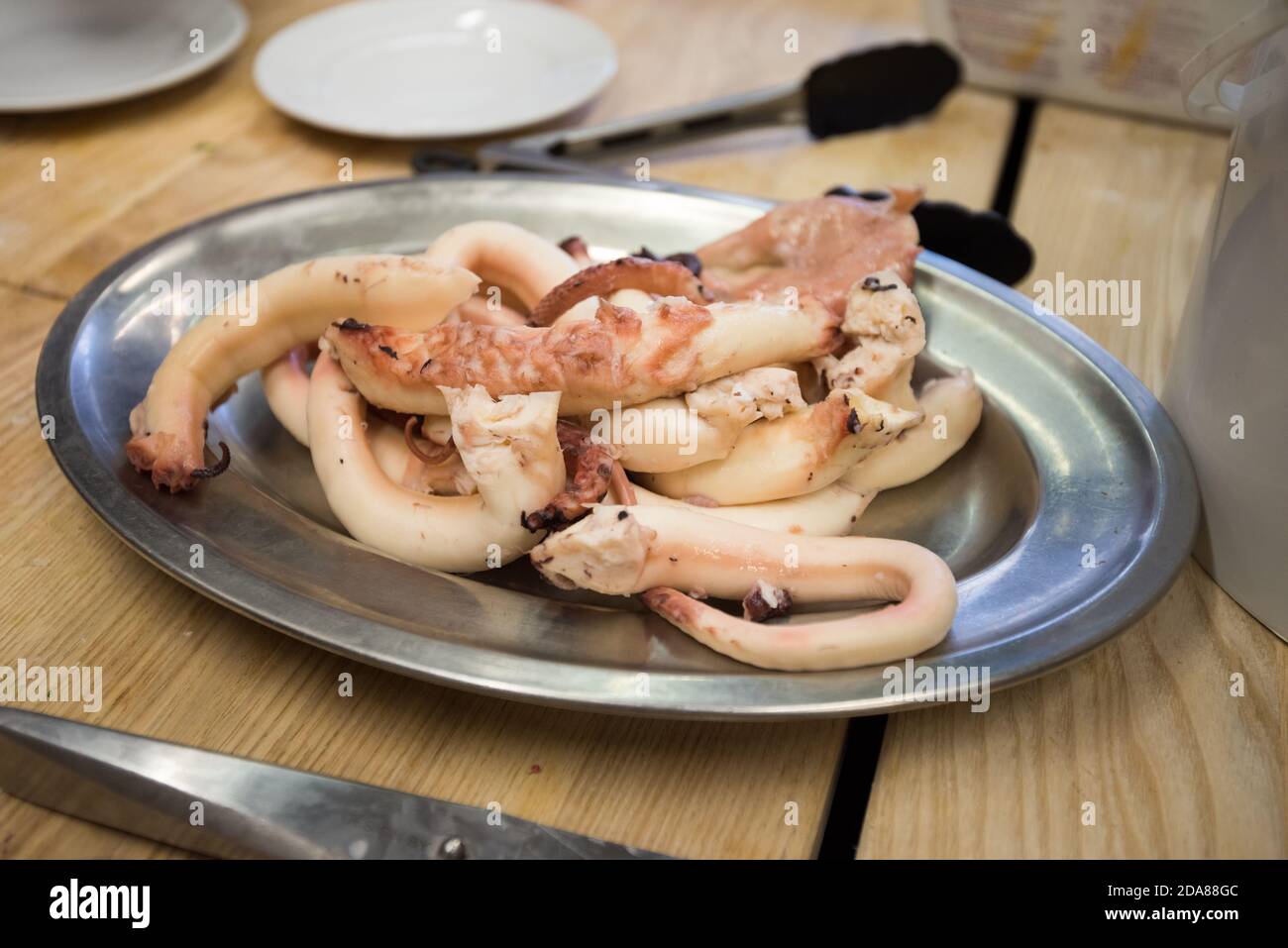 Cooked and skinned pieces of octopus lying on silver plate ready for ...
