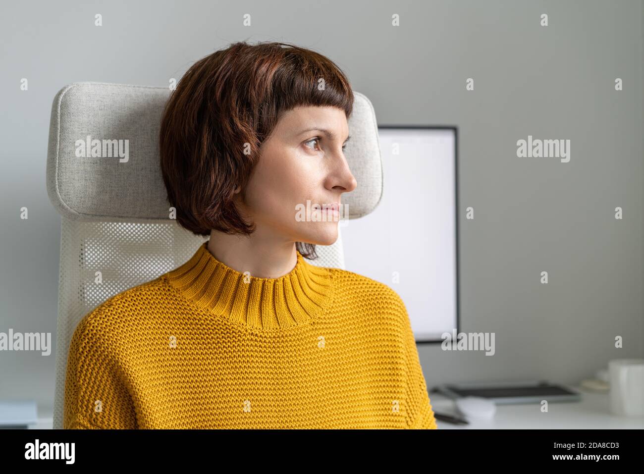 Woman looking out window and taking break from working on computer ...