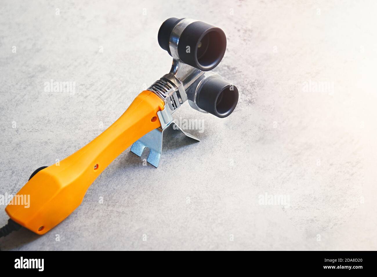 Yellow soldering iron for PVC pp pipes on a grey background, plumbing