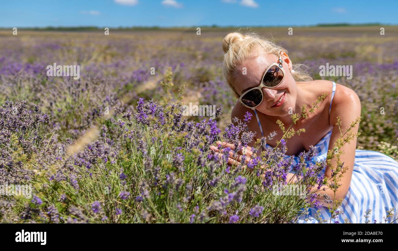 Happy girl on a lavender field with charismatic appearance sunglasses having joyful with white skin stands Stock Photo