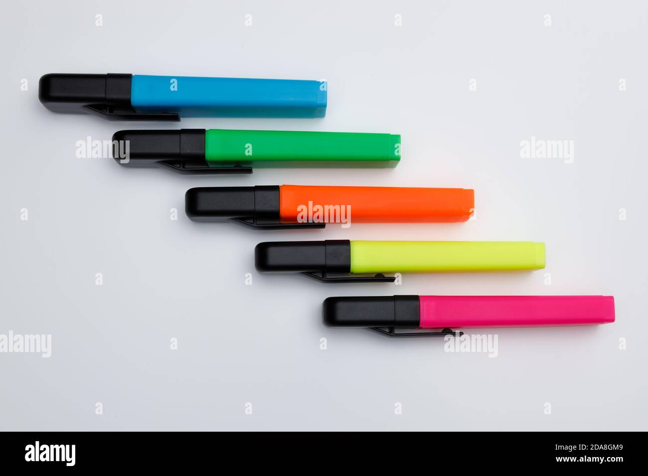 Top view of highlighter pens with closed caps in neon clolors on white uniform background