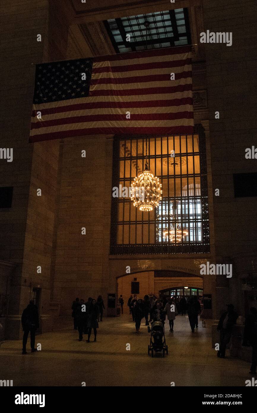 Entrance to Grand Central Station with flag and chandelier and people entering and exiting, Manhattan, New York City, NY, USA Stock Photo