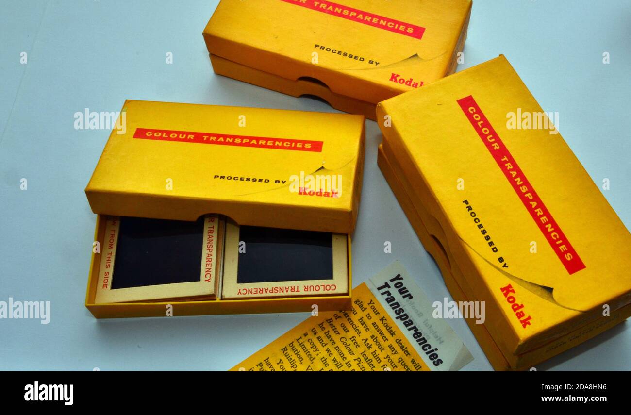 An overhead studio shot of vintage, old Kodak 4 x 4 cm slides in an open Kodak brand colour transparencies box with similar boxes beside it. Stock Photo