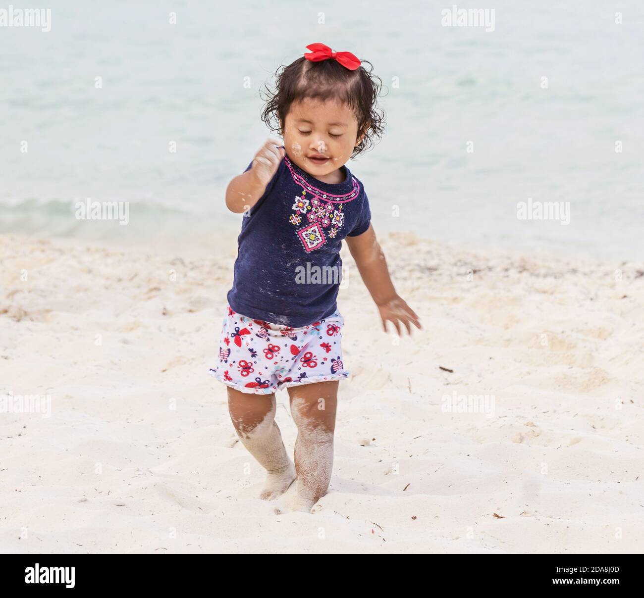 Pretty little mexican girl on beach, with sand ans sea, for editorial use Stock Photo