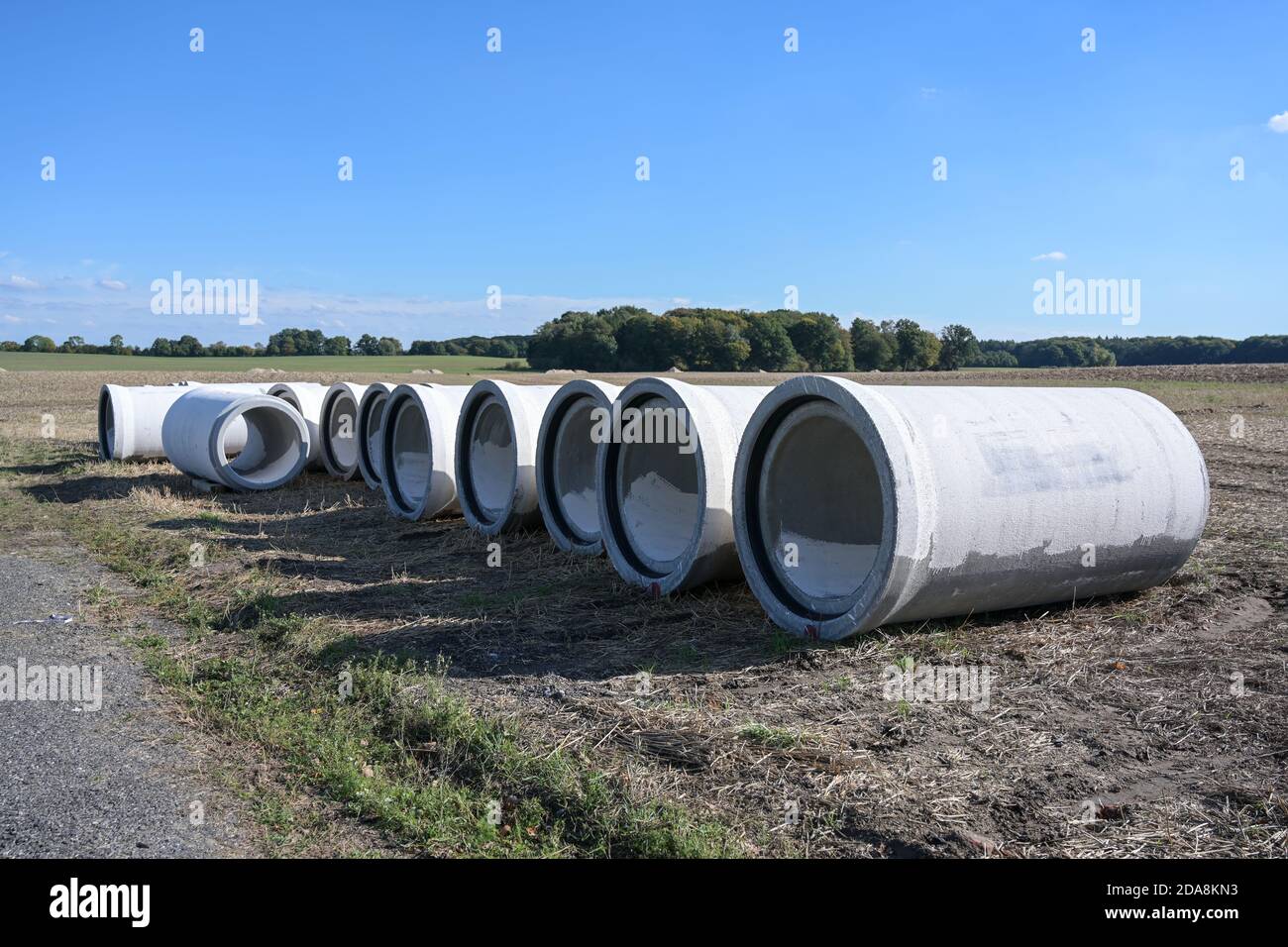 Large concrete water pipes lying on a construction site on a field to build a drainage sewage system against flooding, copy space, selected focus Stock Photo