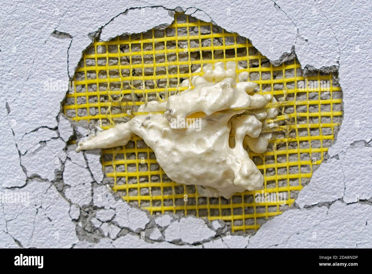 Big hole in wall with expanded foam repair try Stock Photo Alamy
