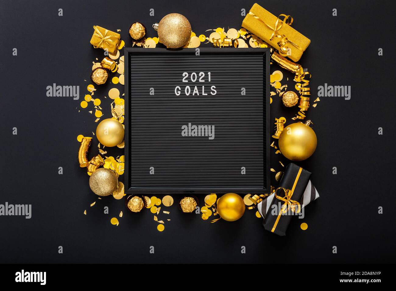 2021 Goals text on black Letter Board in frame made of gold Christmas festive decor, gift boxes, confetti balls. New year 2021 goals, resolution Stock Photo
