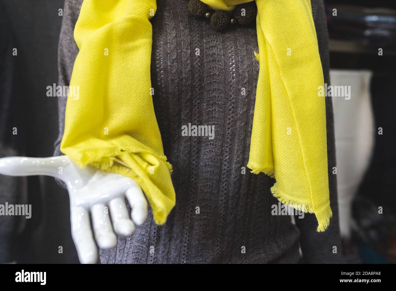 yellow scarf on a mannequin, person in a brown cashmere sweater and yellow shawl, textile products in a showroom, trending fashion Stock Photo