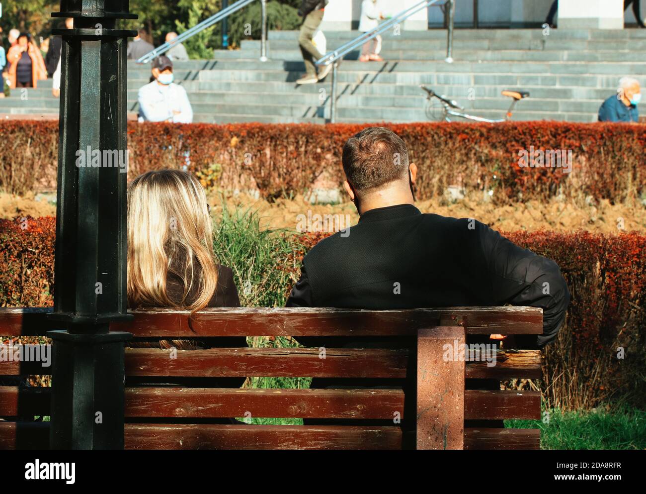 A woman and a man sitting on a bench in the park Stock Photo - Alamy