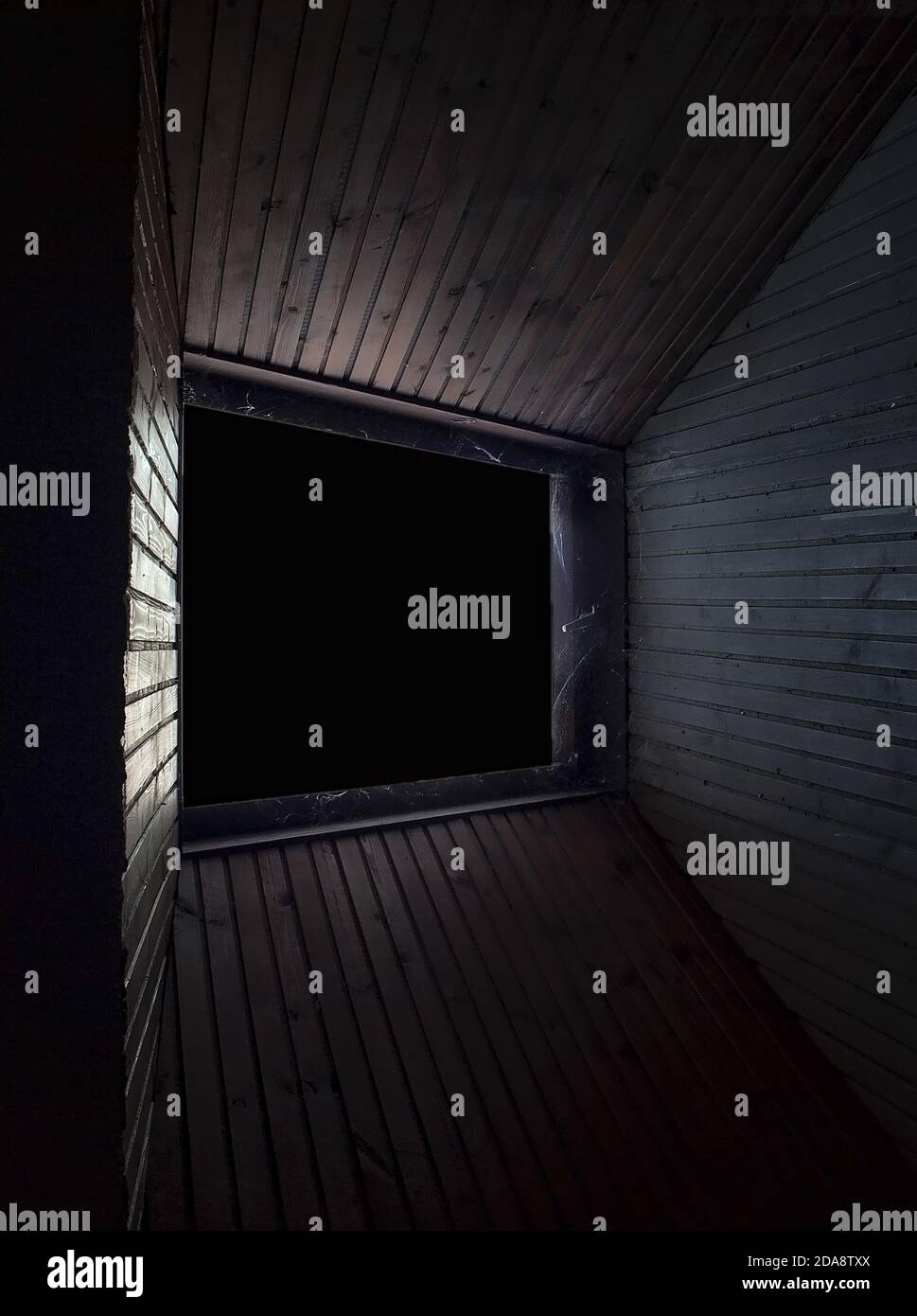Interesting perspective of window in spooky attic and wooden paneling. Dark and lot of dust. Stock Photo