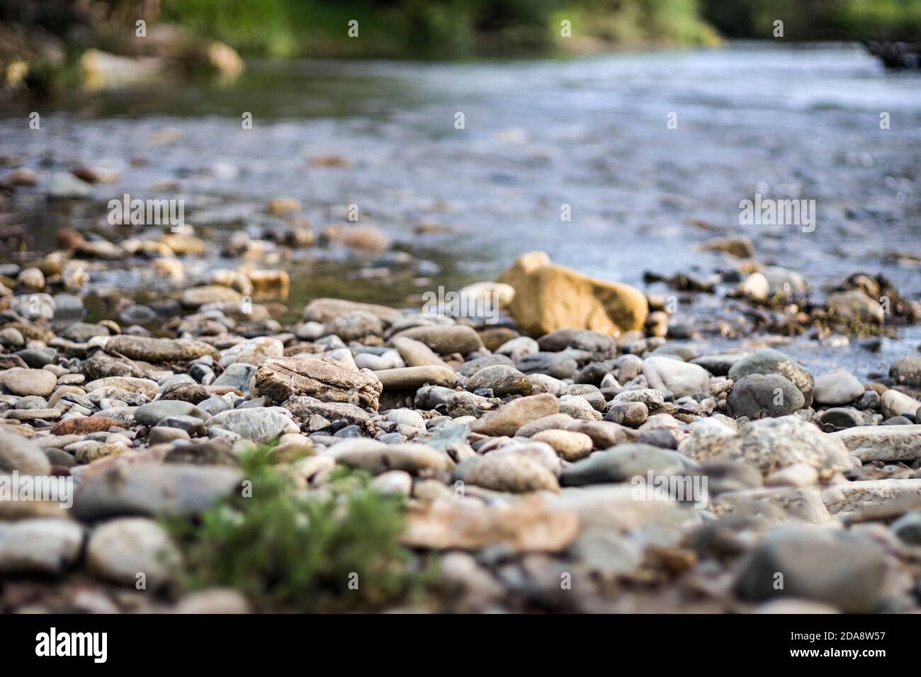 A lot of small stones and pebbles on the river coast. Shallow depth of field, blurred background. Stock Photo