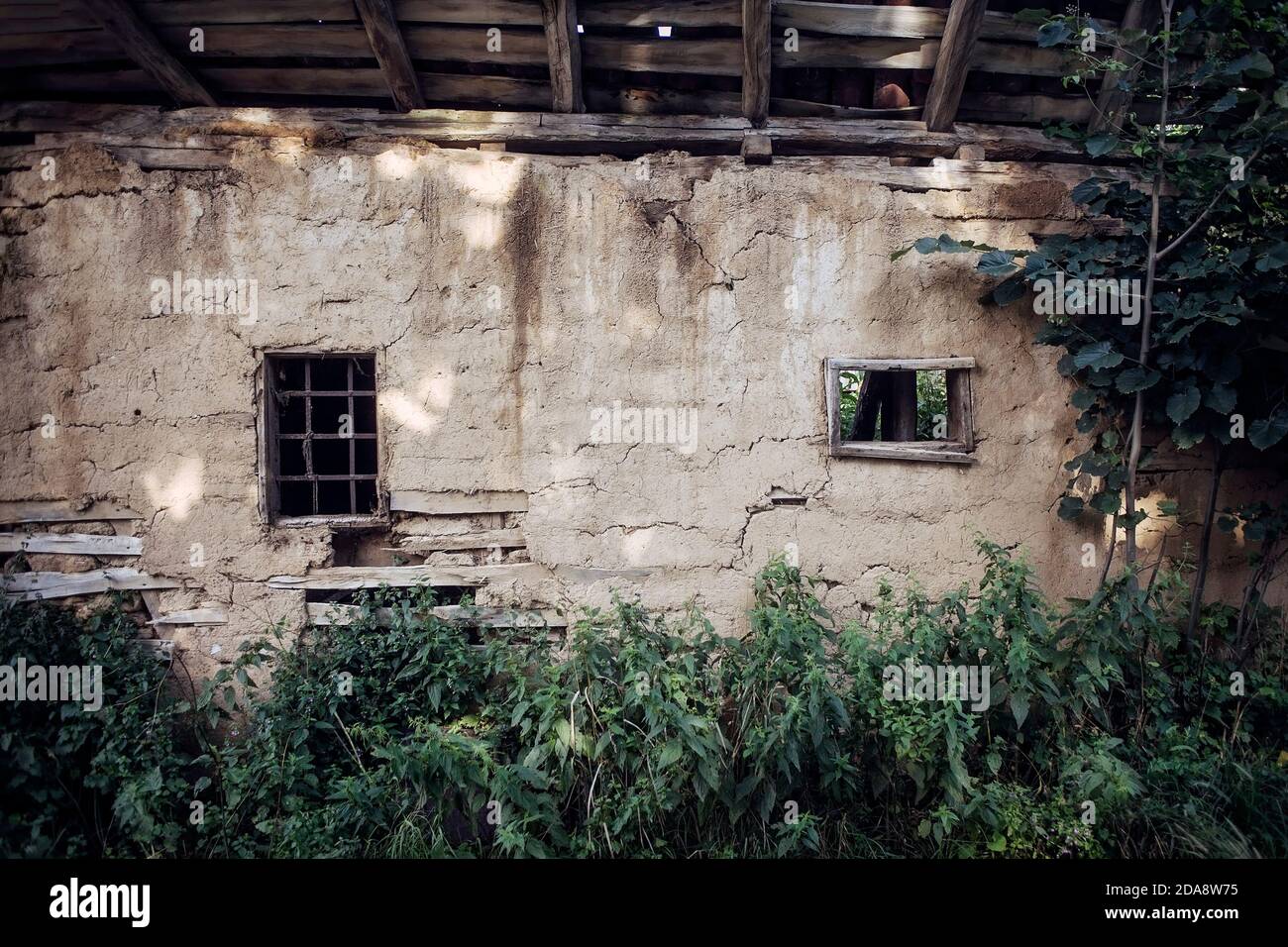 Adobe wall with two windows of an abandoned house in Serbian village. Stock Photo
