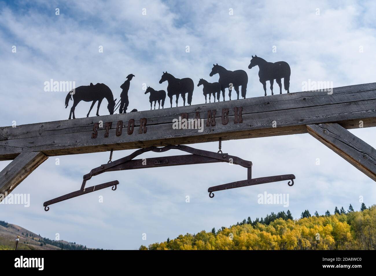 A ranch gate in Idaho with a metal western sculpture and a wagon