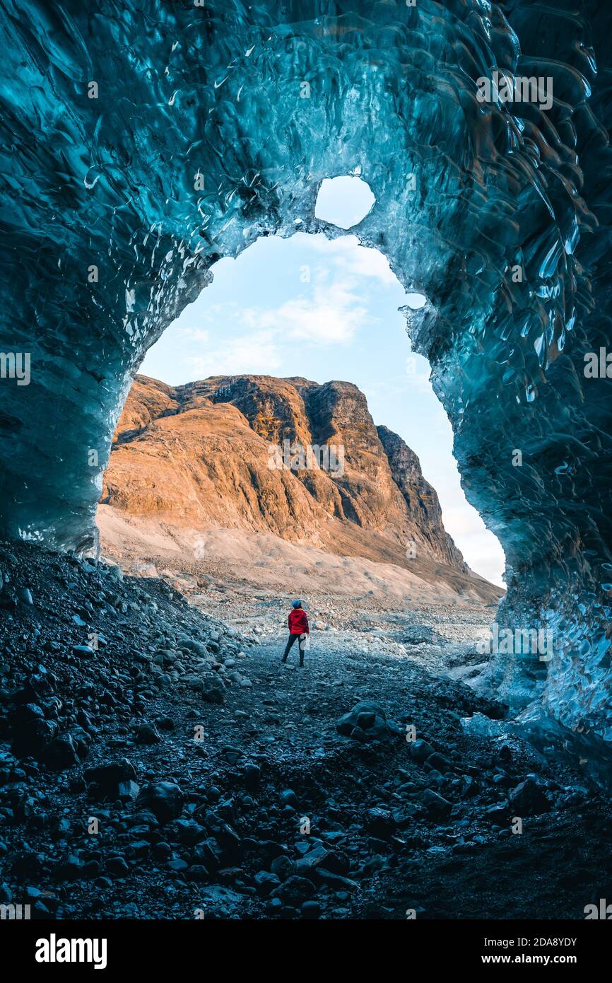 Solo female adventure traveler is discovering the ice caves in Iceland at Vatnajokull Glacier near to Jokulsarlon Glacier Lagoon. Tourism in abandoned Stock Photo