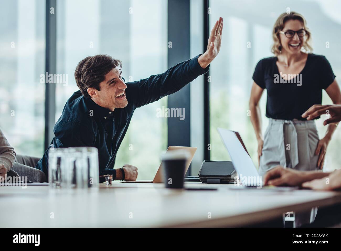 Smiling businessman giving a high five to his coworker sitting around