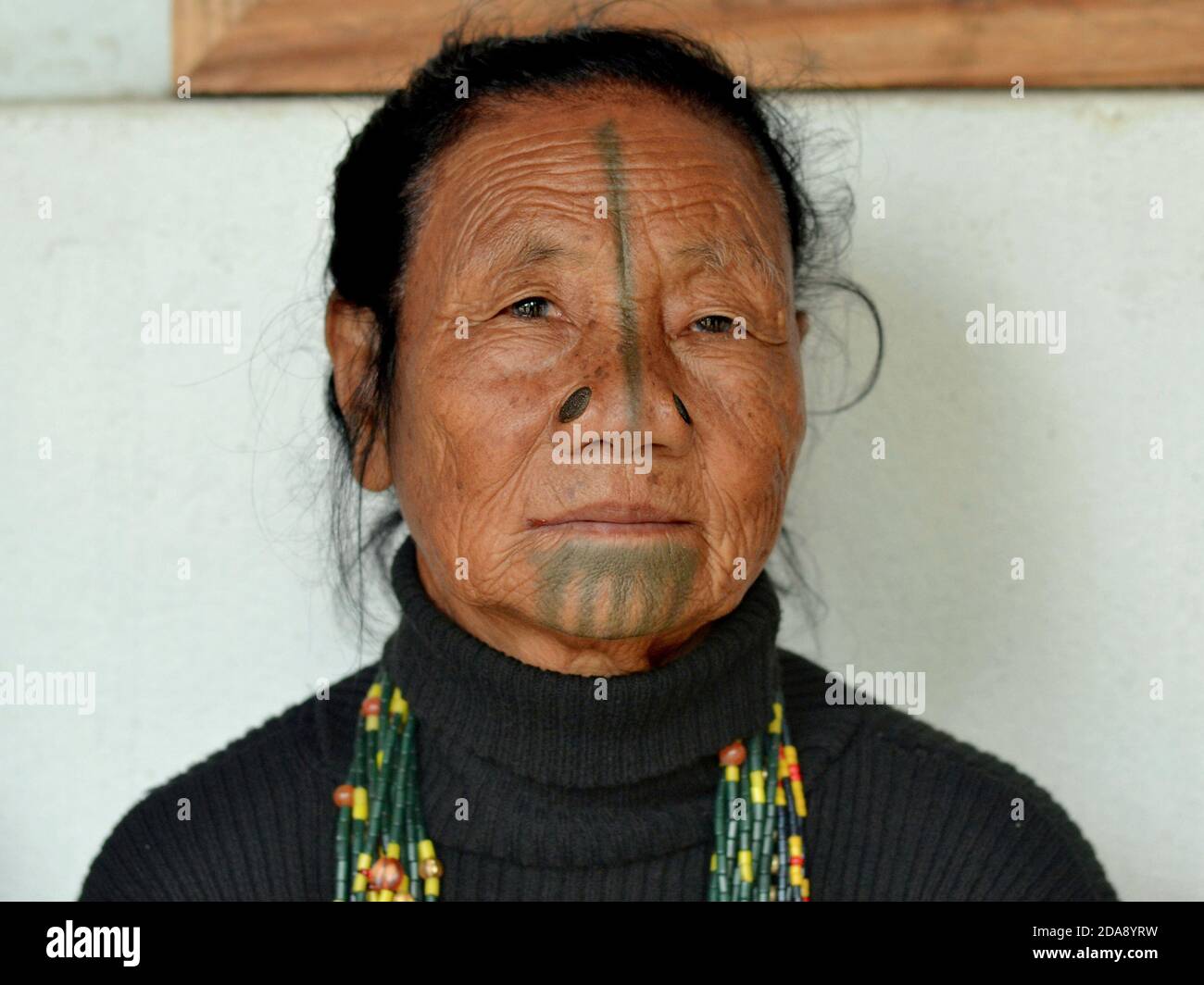 Elderly Northeast Indian Apatani ethnic minority tribal woman with black wooden nose plugs and traditional face tattoos poses for the camera. Stock Photo