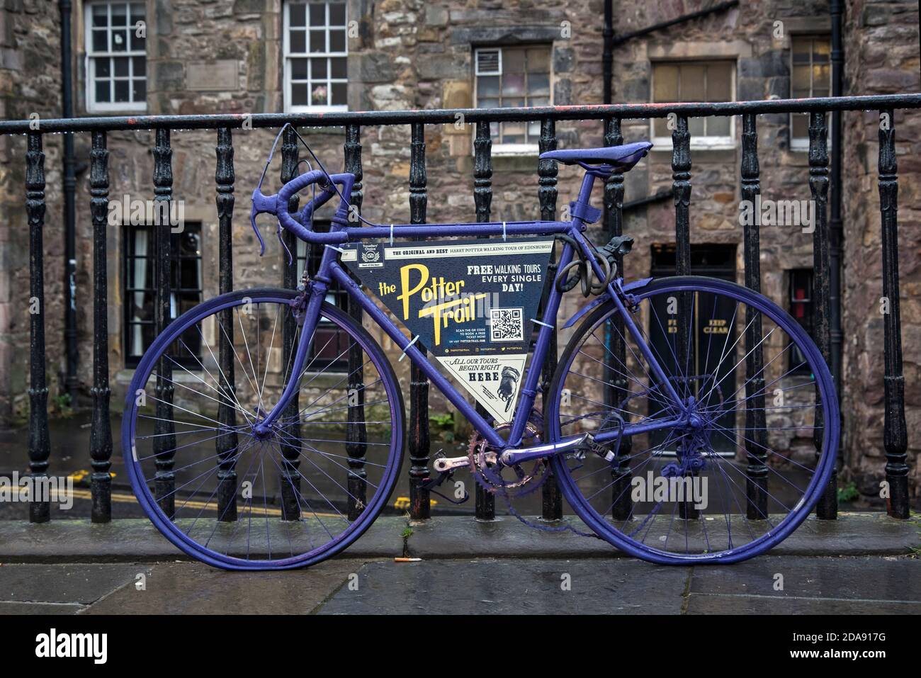 Purple bicycle adverting The Potter Walking Trail attached to railings outside Greyfriars Kirkyard on George IV Bridge, Edinburgh, Scotland, UK. Stock Photo