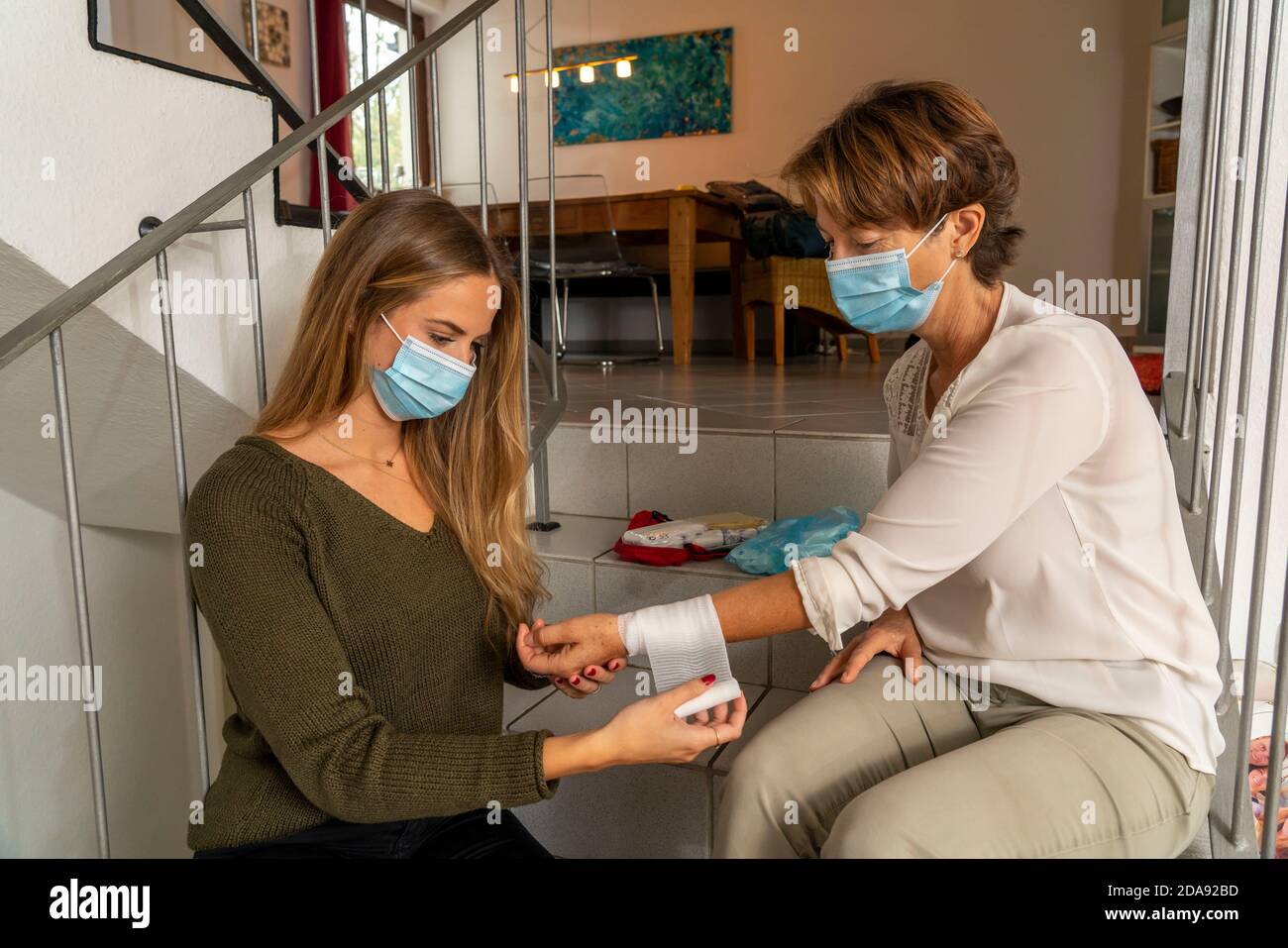 First aid measures under corona conditions, application of a bandage, after an accident in the home, with a nose-and-mouth mask, when giving first aid Stock Photo