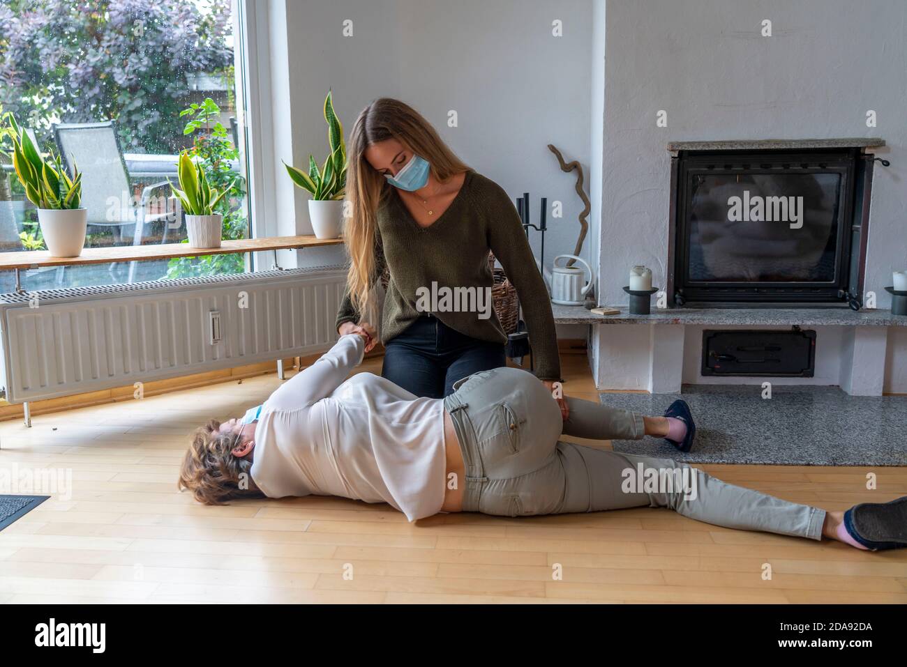 First aid measures under corona conditions, stable lateral position, after an accident in the home, with a mouth and nose mask, when first aid is give Stock Photo