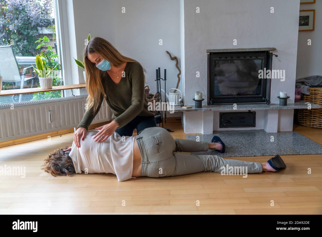 First aid measures under corona conditions, stable lateral position, after an accident in the home, with a mouth and nose mask, when first aid is give Stock Photo