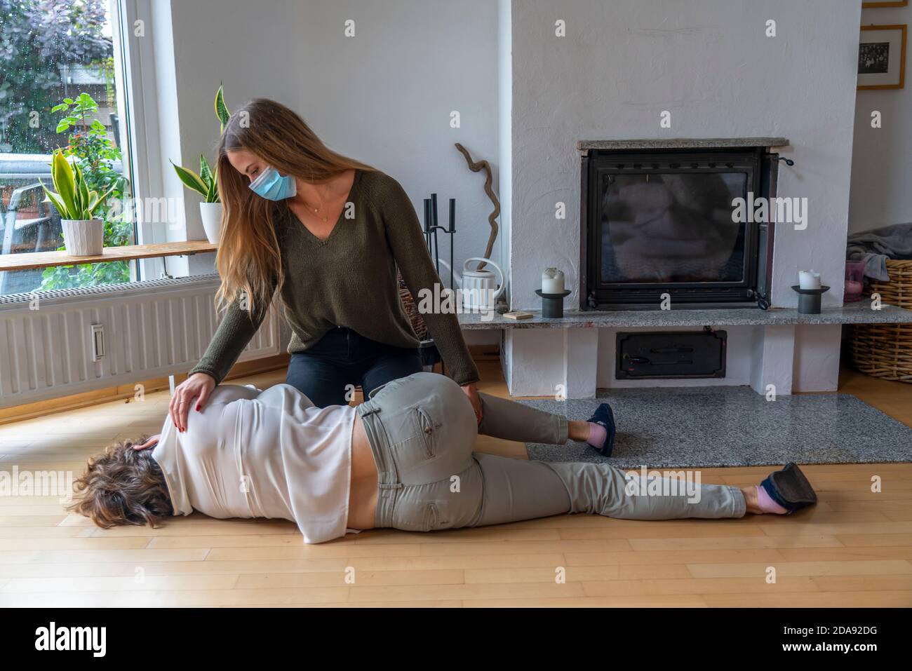 First aid measures under corona conditions, stable lateral position, after an accident in the home, with a mouth and nose mask, when first aid is give Stock Photo