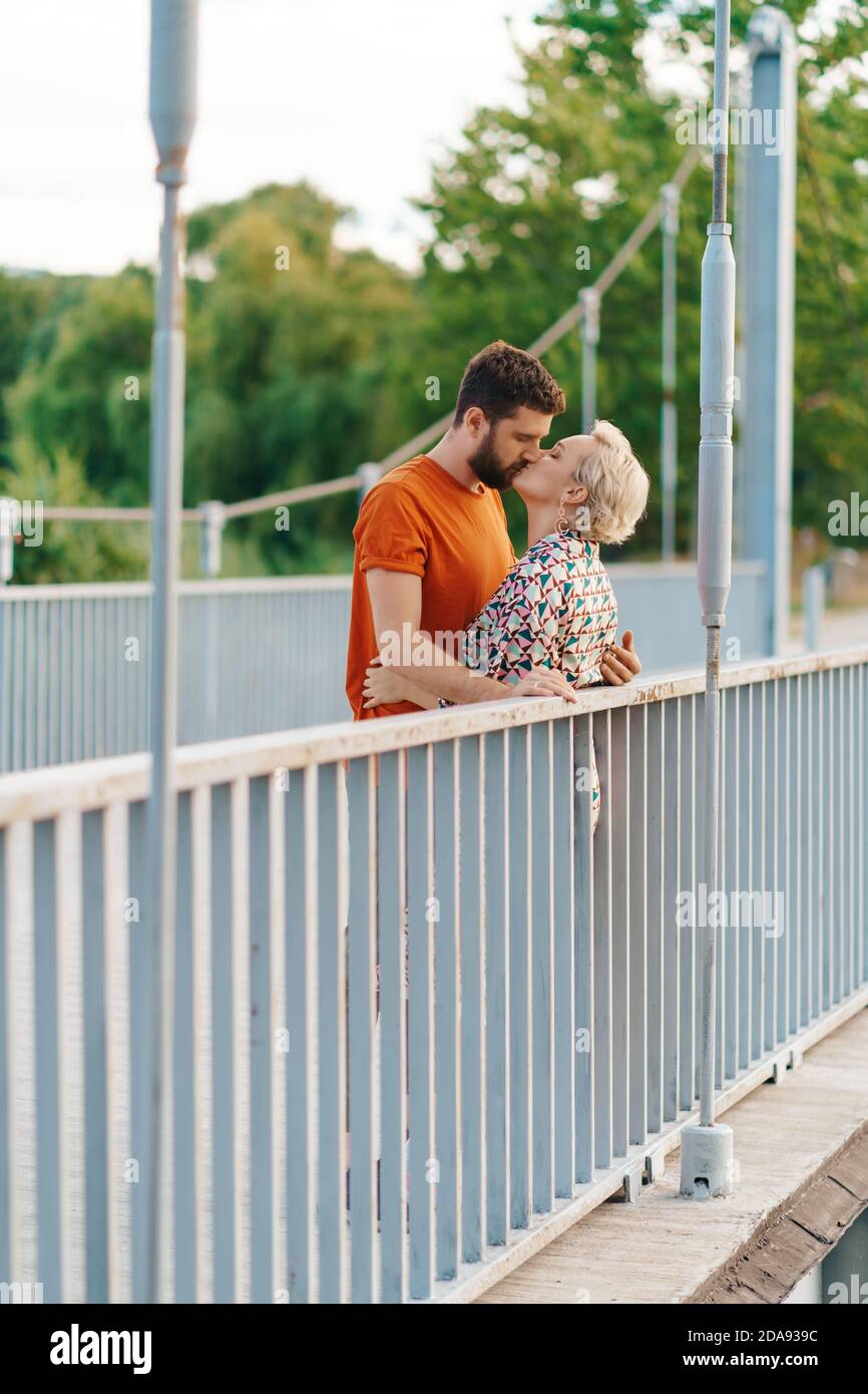 Happy smiling young couple hugging and kissing on bridge Stock Photo ...