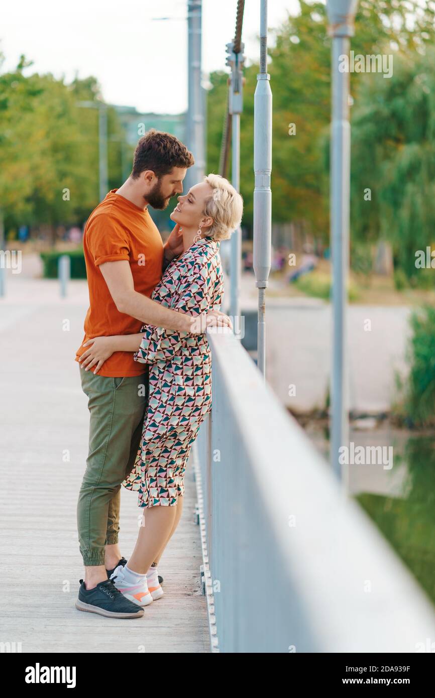 Happy smiling young couple hugging and kissing on bridge Stock Photo ...