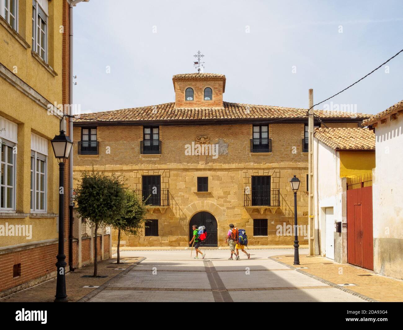 Pilgrims pass by a strong, solid, Navarran style house on the Camino - Uterga, Navarre, Spain Stock Photo