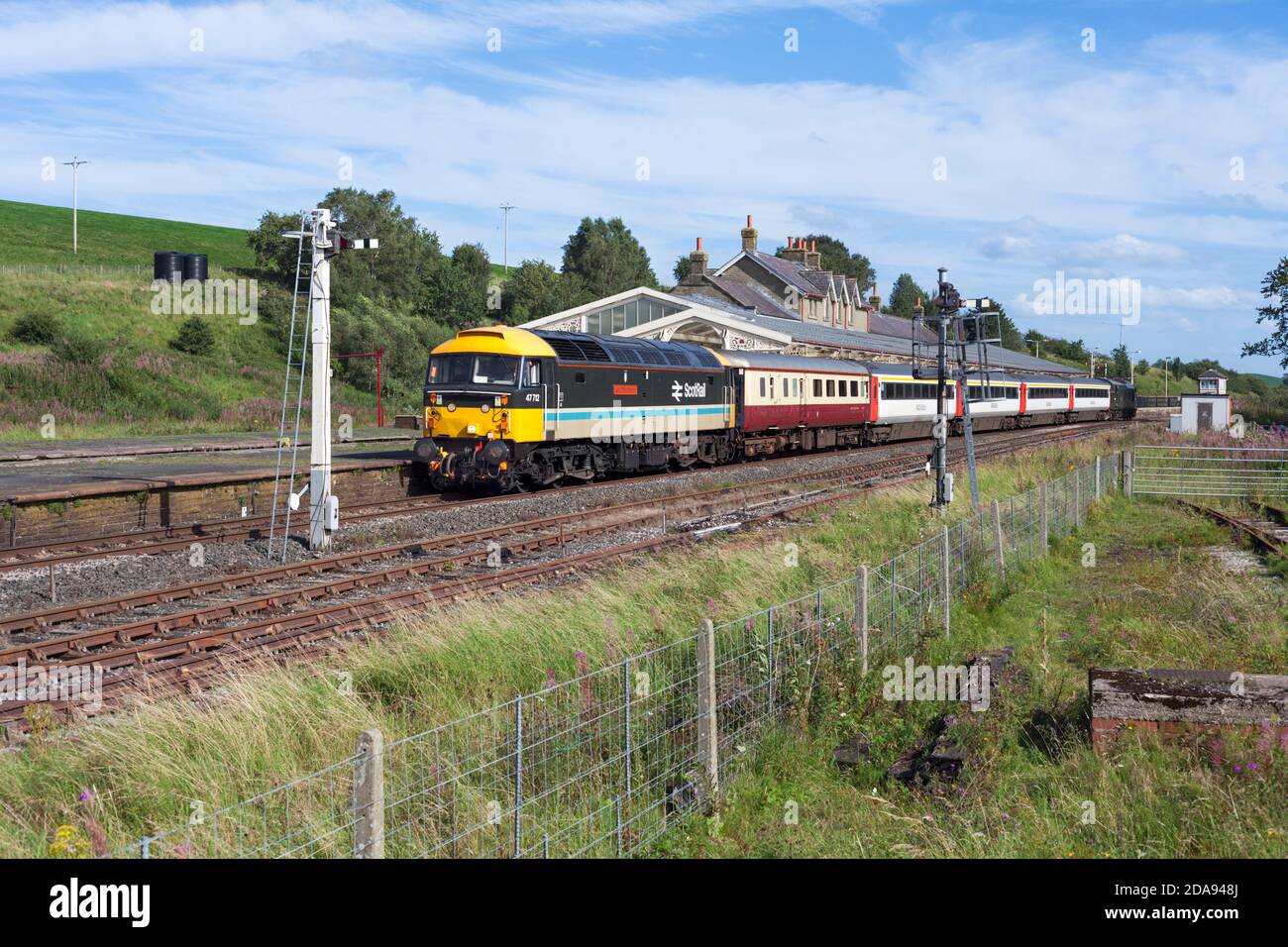 Locomotive services class 47 locomotive 47712 passing the Midland railway station at Hellifield with the 'Staycation Express' tourist train Stock Photo