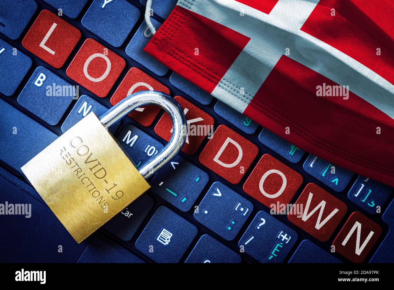 Denmark COVID-19 coronavirus lockdown restrictions concept illustrated by padlock on laptop red alert keyboard buttons and face mask with Danish flag. Stock Photo