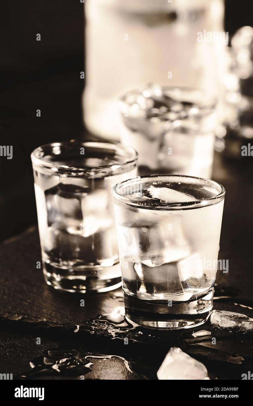 Frozen Vodka in shot glasses on black background, iced strong drink Stock Photo