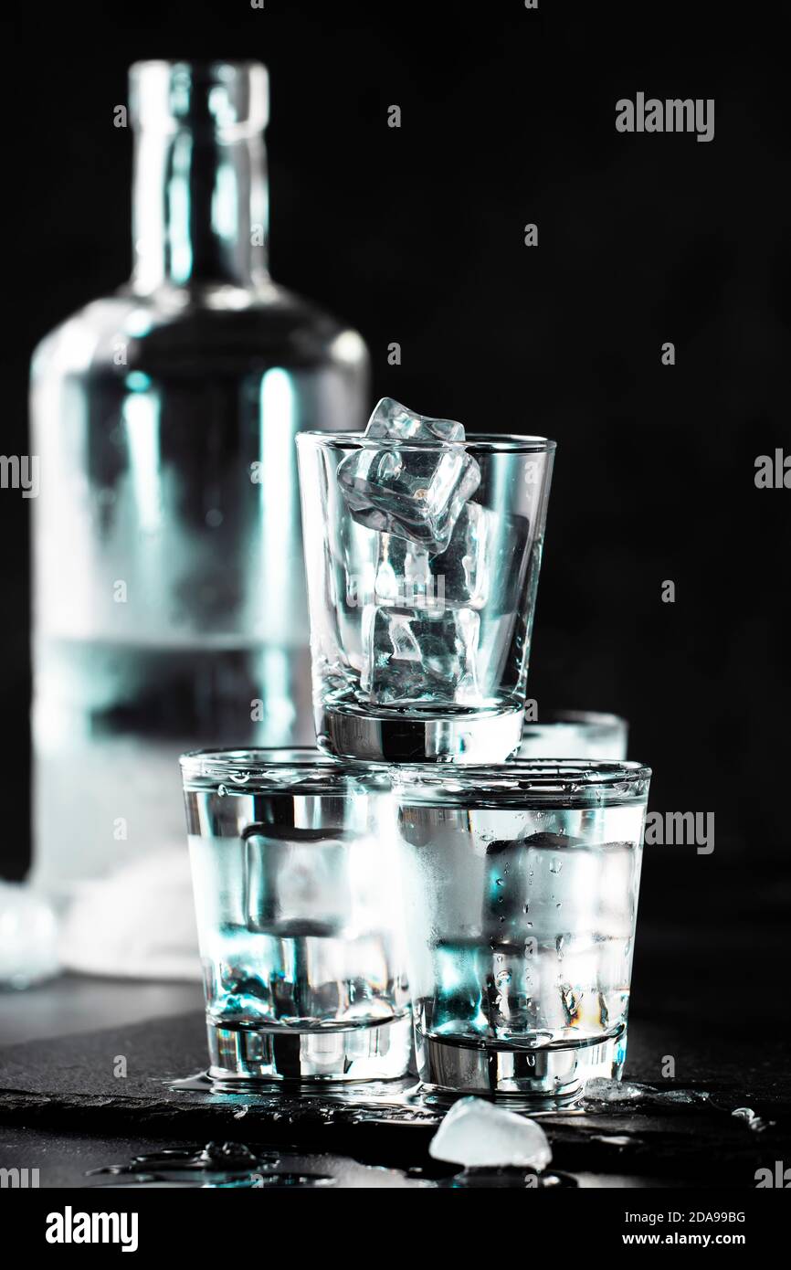 Frozen Vodka in shot glasses on black background, iced strong drink Stock Photo