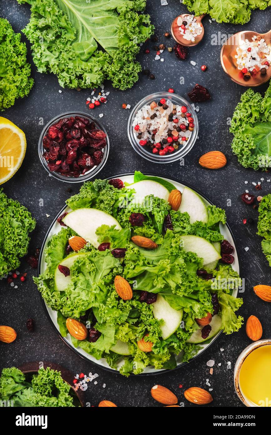 Vegan Kale salad with dried cranberry, apples and almonds. Healthy food, top view, black kitchen