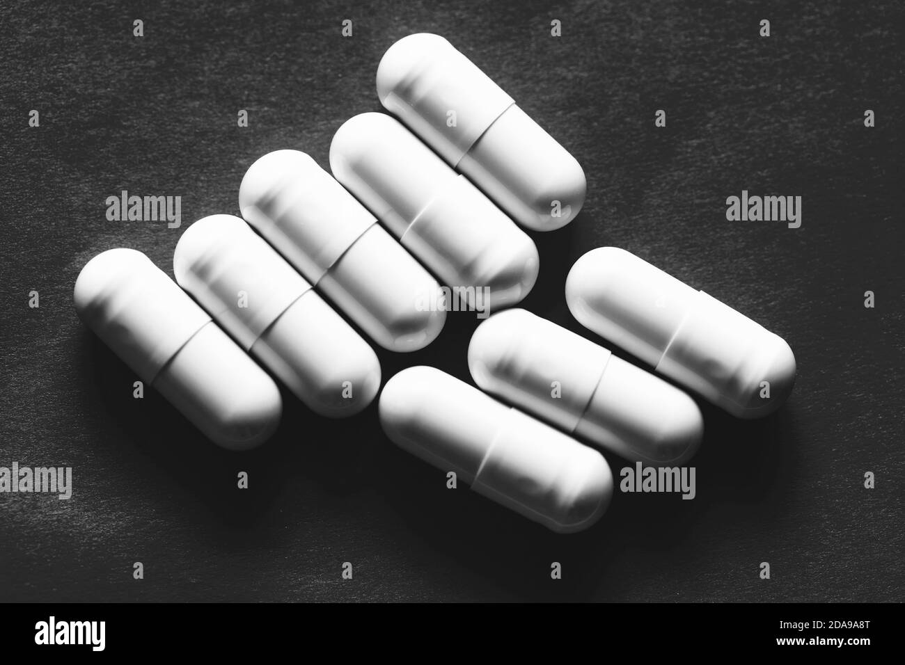 White pills in capsules at black background Stock Photo