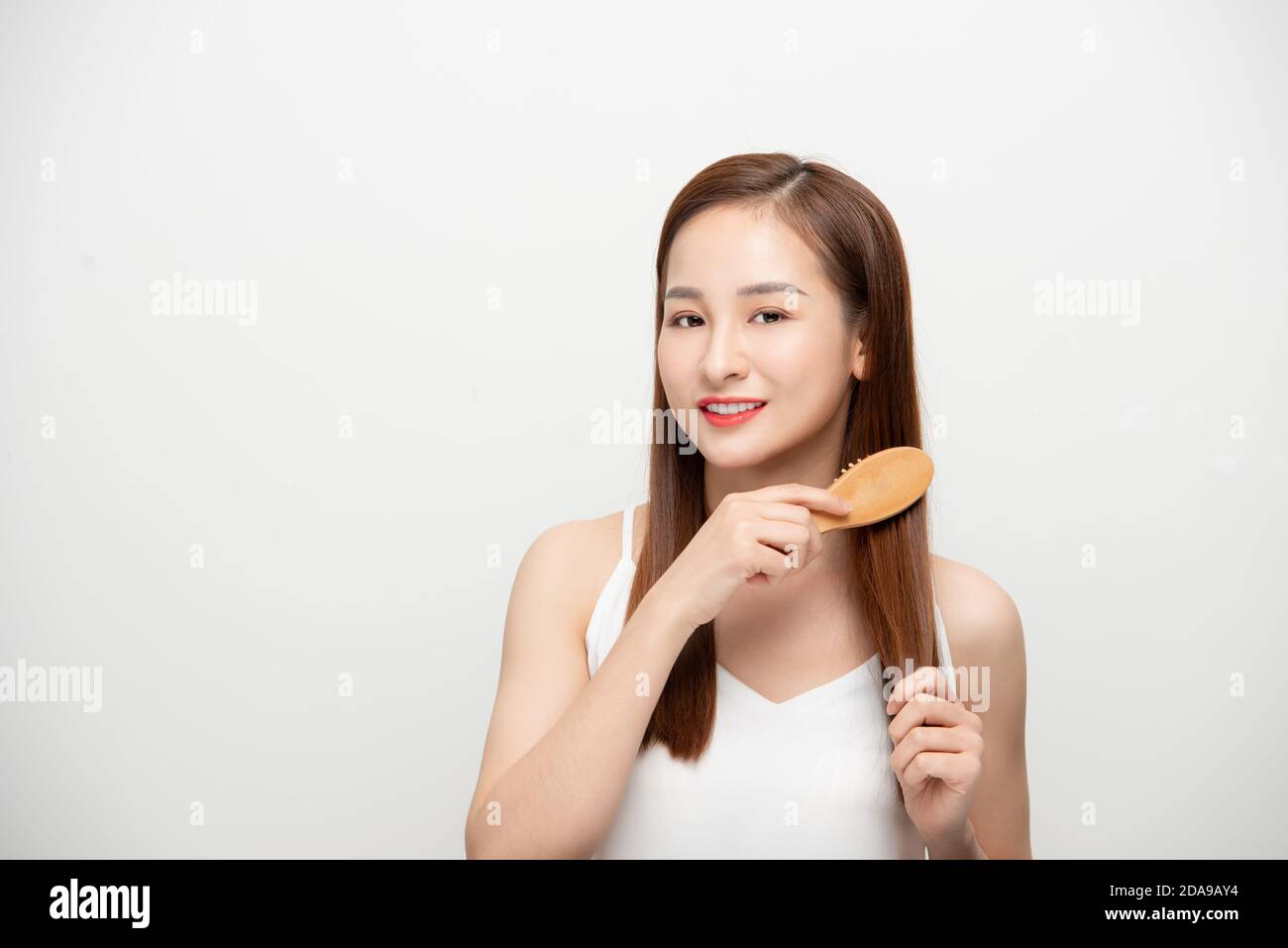 Happy young Asian woman combing her hair. Stock Photo