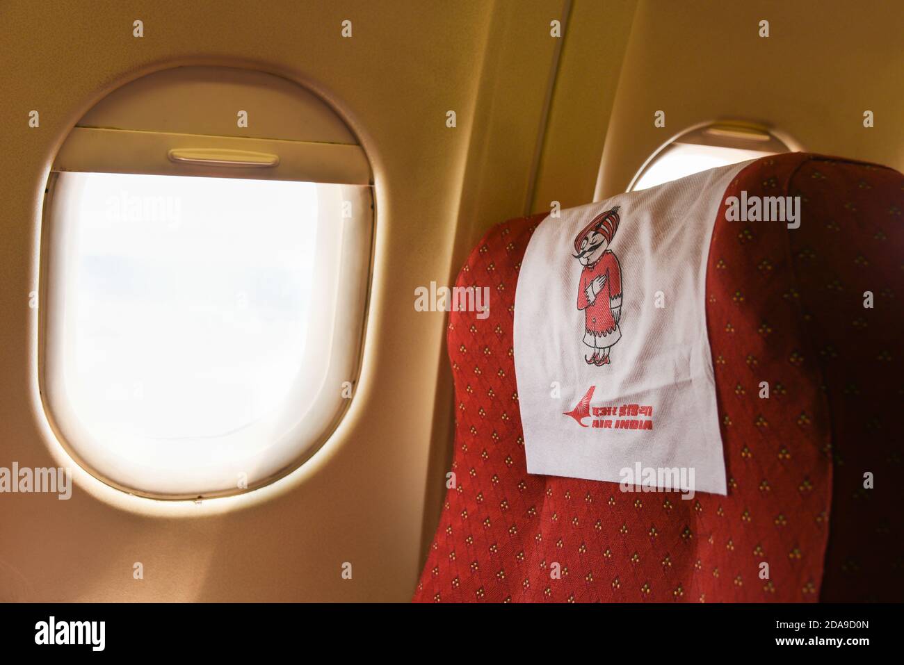 Indian airlines cabin of an Air India (AI) plane. Star Alliance Happy Indian girl traveling by an airplane. Child sitting by aircraft window India Stock Photo
