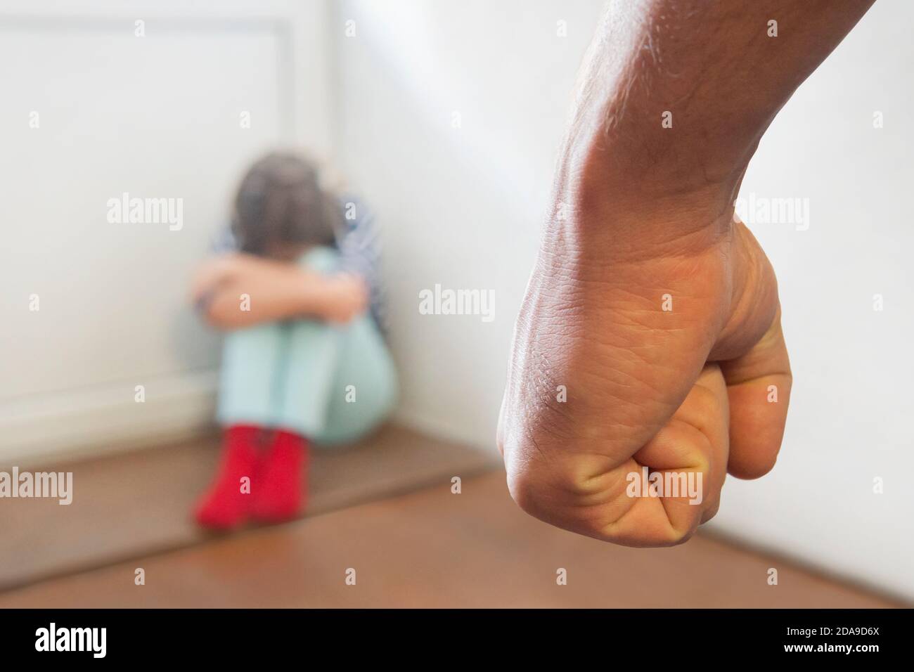 the concept of domestic violence in the family. The girl is crying in the corner. A father punishes his daughter for disobedience. The problem of juve Stock Photo