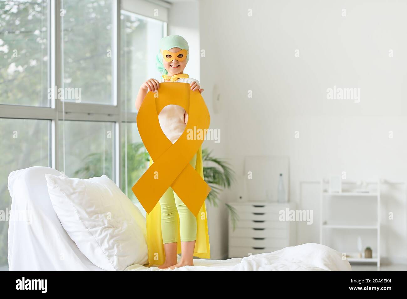Little girl with golden ribbon wearing superhero costume in clinic ...